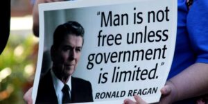 Blog Libertarianism: An image of someone holding up a poster of Ronald Reagan with the quote "Man is not free unless government is limited".