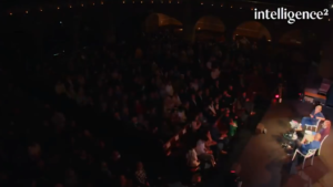 Blog Saving capitalism: Image of the auditorium, showing Gillian Tett, Ann McElvoy, and Yanis Varoufakis on stage in the lower right and the audience in the auditorium.