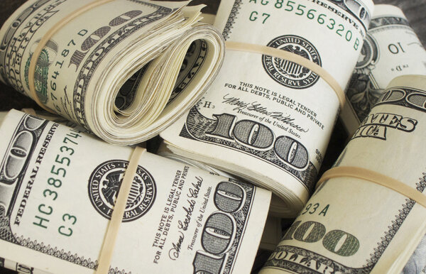 How we can better understand what causes inflation? What causes inflation: Image shows a bunch of rolls of USD hundred dollar bills